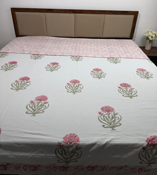 Bed with floral patterned bedspread against a white wall