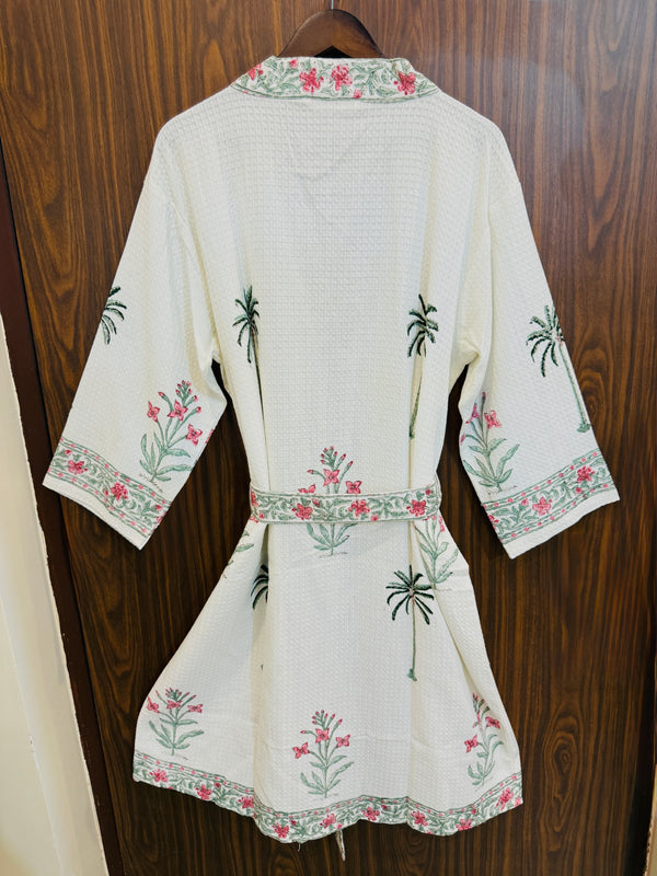 White embroidered garment on a wooden hanger against a wooden background