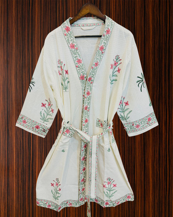 White embroidered robe with floral patterns on a wooden background
