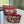Three small zippered cosmetic pouches with a red and cream floral damask pattern, arranged on a white marble countertop near a window.