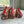 Three small zippered cosmetic pouches with a red and beige floral pattern, arranged on a white marble countertop in front of a window.