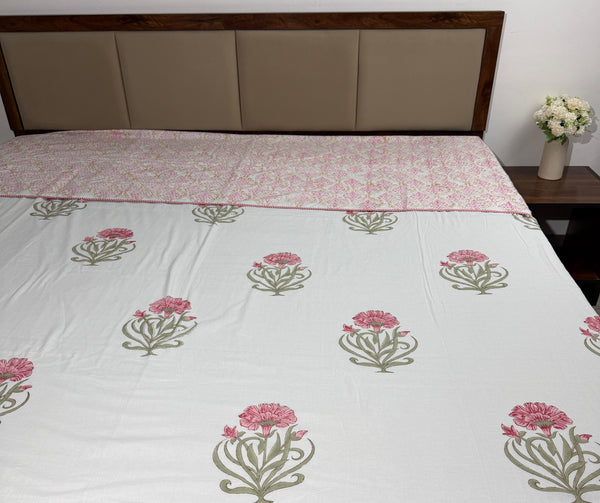 Floral patterned bedspread on a bed with a wooden headboard and nightstand.